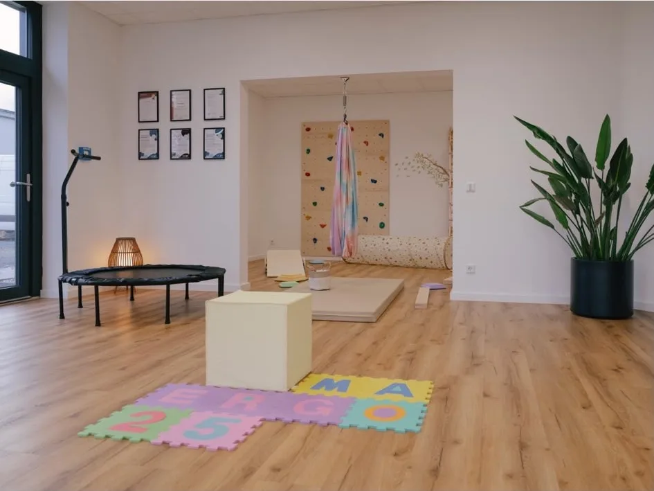 Heller Bewegungsraum mit Trampolin, Kletterwand und Aerial-Tuch für Pädiatrie und Ergotherapie im Therapiezentrum Südkirchen